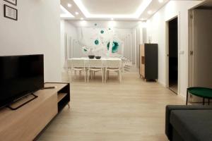 a white living room with a table and a tv at Las Américas Seafront - Free Wi-fi in Costa de Adeje