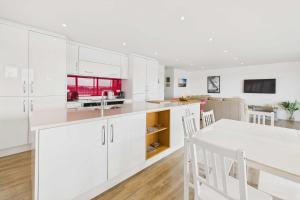 a kitchen with white cabinets and a table and chairs at Host & Stay - Becalmed in Amble +12 photos