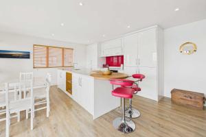een keuken met witte kasten en een rode barkruk bij Host & Stay - Becalmed in Amble +13 foto's