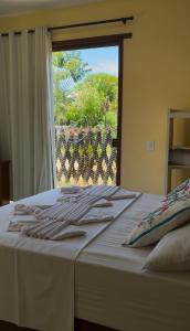 un letto bianco con vista su una finestra di Hospedaria Canto Itaúnas a Itaúnas