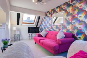 a living room with a pink couch and a colorful wall at Stylish Studio in the Heart of Stamford Perfect Location in Stamford