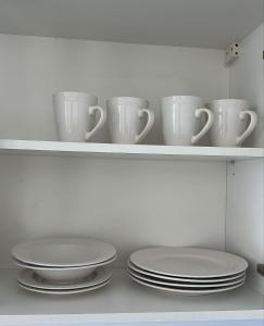a shelf with white cups and plates on it at Altamira Surubi-i in Estancia Sarubi