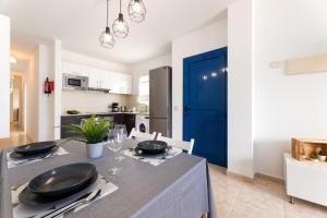 カレタ・デ・ファマラにあるEl Arenal de Famara by Escape Homeの青いドアのテーブルがあるキッチンとダイニングルーム