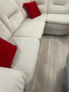 Tjaldstæðið í Tálknafirði býður upp á alla þjónustu في Talknafjordur: أريكة بيضاء مع وسائد حمراء على أرضية خشبية