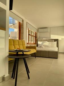 a living room with a yellow couch and a bed at Old Town Charm in Dhërmi