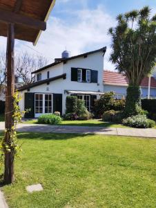 a white house with a palm tree in a yard at Hermoso Chalet 6 personas a cuadras del Mar in Miramar