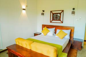 une chambre avec un grand lit avec des oreillers jaunes dans l'établissement Buddothpado International Meditation Center, à Anguruwatota