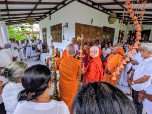 un groupe d'hommes en robes orange debout dans une foule dans l'établissement Buddothpado International Meditation Center, à Anguruwatota