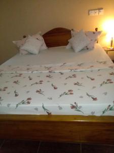 a bed with a white comforter with flowers on it at Mimosha holiday inn in Godapola