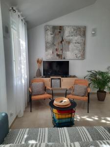 a living room with a table and two chairs and a tv at Gîte le Relais d'Eden in Barbentane