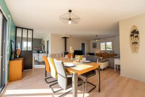 a dining room and living room with a table and chairs at La Villa Océane, familiale & piscine privée in Guidel