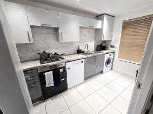 a kitchen with white cabinets and a stove top oven at Spacious 3-Bed Townhouse in Bilston, Sleeps 9, Driveway Parking, Near M6 & Wolverhampton in Bilston