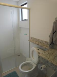 a white bathroom with a toilet and a shower at Praia Mansa Caioba in Matinhos
