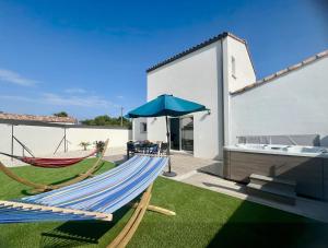 eine Terrasse mit einer Hängematte und einem Sonnenschirm in der Unterkunft Rincon del Mar - Maison & spa privatif in Saint-Hilaire-de-Riez