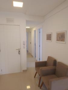 a living room with two chairs and a door at Praia Mansa Caioba in Matinhos