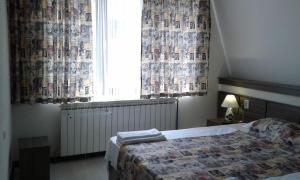 a bedroom with a bed and a window with curtains at Къща за гости Семейство Петрови in Kalofer