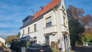 een wit huis met een auto ervoor geparkeerd bij Ferienwohnung Luitpold 21 in Edenkoben