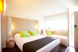 a hotel room with two beds with green pillows at Campanile Lille Nord Wasquehal in Wasquehal +17 photos