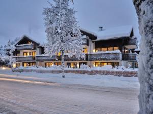 a snow covered building with a tree in front of it at Bader Suites in Garmisch-Partenkirchen