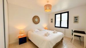 Un dormitorio con una cama blanca y un escritorio. en Charmante location à deux pas de la plage, en Rivedoux-Plage