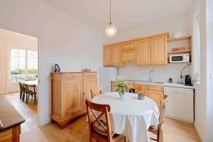 een keuken met een tafel met een witte tafeldoek bij Villa des Genêts in Saint-Pair-sur-Mer