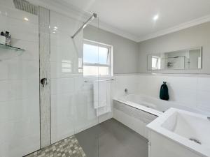 Un baño blanco con bañera y lavabo. en Vida Tranquilo, en Edgemead