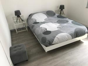 ein Schlafzimmer mit einem Bett mit einer schwarz-weißen Bettdecke in der Unterkunft Apt Baie de Somme en centre ville 200m de la plage in Cayeux-sur-Mer