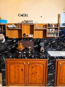 une cuisine avec comptoir en marbre noir et armoires en bois dans l'établissement Siinup Hostel, à Tiznit