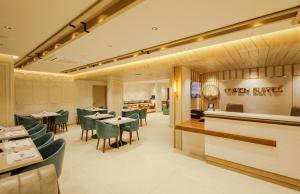 a restaurant with green chairs and tables and a counter at Olwen Suites in Cochin