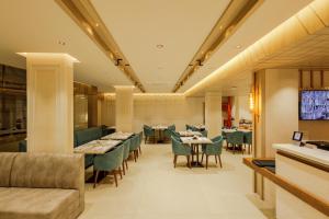 a restaurant with tables and chairs and a couch at Olwen Suites in Cochin