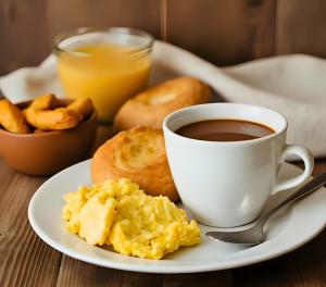 a plate of breakfast food with a cup of coffee at Hotel Lourdes la 62 in Bogotá