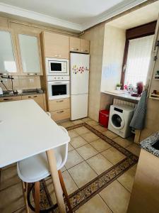 une cuisine avec une table et un réfrigérateur blanc dans l'établissement Acogedor apartamento equipado parque natural Aitzgorri-Aratz, à Araya