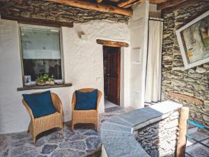 a living room with two chairs and a stone wall at Casa Sorel : Attico Lago & Pool in Pianello Del Lario
