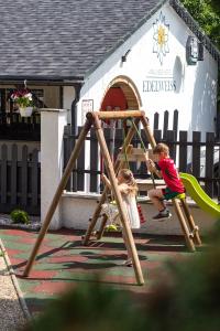 two children playing on a swing set in a playground at Wellness Hotel Edelweiss in Liberec