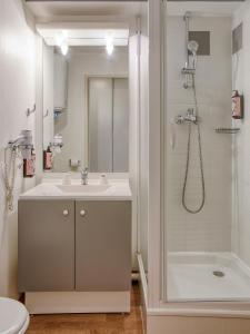 a white bathroom with a sink and a shower at Séjours & Affaires Angers Atrium in Angers