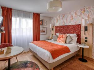 a bedroom with a large bed and a red wall at Séjours & Affaires Angers Atrium in Angers
