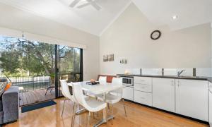a kitchen with white cabinets and a table and chairs at Beach Shack 6 in Preston Beach