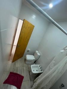 Un baño con inodoro y puerta de madera. en Cabañas del monte, en Monte Hermoso
