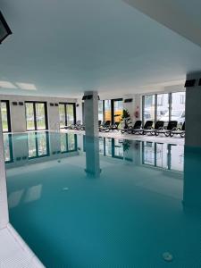 une piscine avec des chaises dans un immeuble dans l'établissement Nadmorski Apartament z dostępem do basenu, sauny, jacuzzi i ogródkiem przy plaży 114 Rezydencja Niechorze, à Niechorze