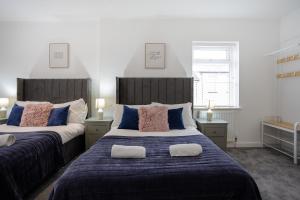 1 Schlafzimmer mit 2 Betten mit blauen und rosa Kissen in der Unterkunft Bespoke Apartments Near Cardiff City Centre Free Parking in Cardiff