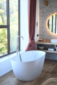 a large white bath tub in a bathroom with windows at La Grange de Magdeleine in Salles-la-Source
