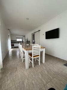 Un comedor con una mesa y sillas blancas. en Cabaña del monte 1, en Monte Hermoso