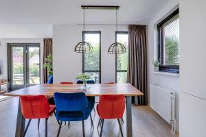 a dining room with a wooden table and red and blue chairs at Groenlake Villa 6p Vakantie bungalow in Ewijk