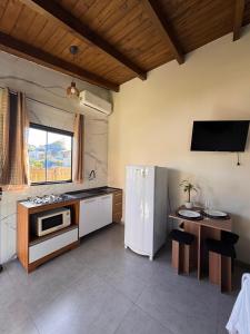 a kitchen with a white refrigerator and a table at Pousada Tudix in Praia do Rosa