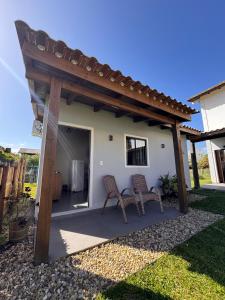 a patio with two chairs under a pergola at Pousada Tudix in Praia do Rosa +23 photos