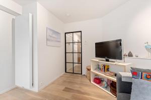 a living room with a flat screen tv on a stand at Sparrenduin - Compact en cosy app aan golf De Haan in De Haan