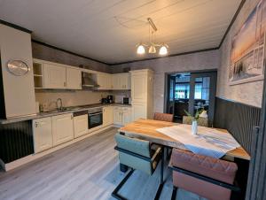 a kitchen with white cabinets and a wooden table at Ferienwohnung Landkajüte in Twist