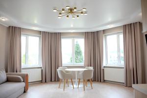 a living room with a table and chairs and windows at Elata Aparts in Skhidnitsa