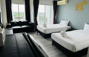 a hotel room with two beds and a couch at Golden Good View Hotel, Chiang Mai in Chiang Mai