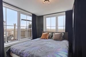 a bedroom with a bed and windows with a view at Tiny House in Westdorpe